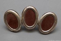 Front view of antique 925 sterling silver triple oval photo frame showing three connected oval frames with brown backing material inside each frame.