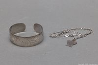 Silver cuff bangle showing etched personalized design and slight patina wear