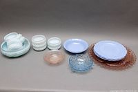 Full view of the various milk glass plates, bowls and depression glass items arranged with different colors and sizes