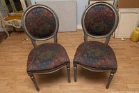 Front angle view of two vintage accent chairs seated side by side showing overall condition and upholstery pattern.