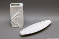 White porcelain vase and matching serving dish on gray background.