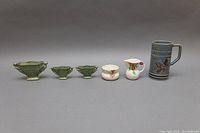 Full view showing the complete lot of six ceramic items including beer mug, mermaid bowls, creamer and sugar bowl.