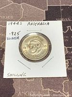 Reverse side of 1944 Australian silver shilling coin in protective holder showing ram and inscriptions.