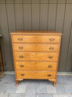 Front view of antique cherry wood country dresser, showing five drawers with metal bail pull handles and keyholes, standing on bracket feet.