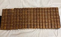 Front view of 24 leather bound volumes of George Eliot's complete works, showing titles and gilt decorations on spines.
