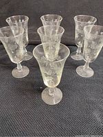 Seven antique EAPG parfait glasses arranged on a dark fabric background showing overall set and design.