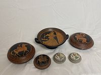 Overall grouping of six Greek pottery replica pieces showing designs and relative sizing