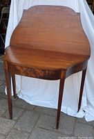 Full view of closed mahogany folding card table showing shape and tapered legs
