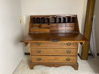 Front view with drop leaf open revealing multiple small drawers and pigeonholes inside the desk.