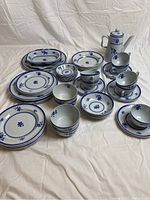 Full set layout showing all plates, bowls, cups, trays, and server in blue and white floral pattern design.