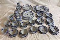 Full set of Spode Gloucester Copeland china laid out on fabric surface, showing plates, bowls, cups, saucers, and serving pieces all with a blue floral pattern.