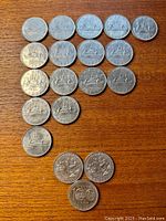 Close view of 1970, 1972, 1975 Canadian one dollar coins and some centennial coins including Manitoba 1970 and Winnipeg 1974 on wooden surface.