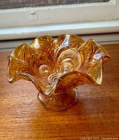 Side view showing the ruffled edge and intricate pressed patterns of the marigold carnival glass vase.