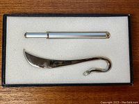 Pen and bookmark set in black box with foam padding. Pen is silver-tone with gold accents, bookmark is silver with a pearl at the hook end.