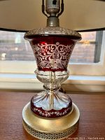 Close-up of the ruby cut to clear crystal portion of the lamp showing floral and scroll etching details and gold-tone metal base.