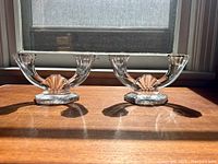Pair of double arm crystal candelabras displayed side by side, in sunlight, showing overall design and size.