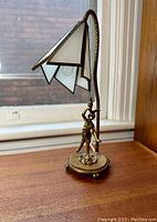 Full side view showing the entire lamp with the stained glass tulip shade and brass figure base.