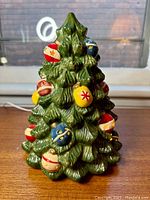 Front view of the glossy green ceramic Christmas tree featuring red, blue, yellow, and brown bulb ornaments with star and stripe patterns.