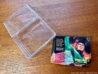 Clear hinged plastic case beside a stack of colorful Marvel Masterpieces TCG cards featuring Wrecker card visible.