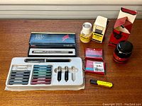 Lot of vintage Sheaffer and Parker pens and supplies arranged on wooden surface under window light.