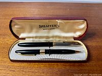 Sheaffer pen and pencil set in burgundy case with cream satin interior, showing both items paired.