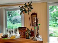 Photo showing Bombay style metal candle holder, various glass candle holders, faux fruit plant in a planter, and tall slender metal candle holder.