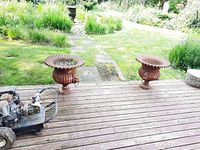 Two urns on wooden deck with garden backdrop