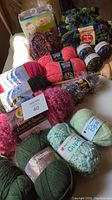 Overview of assorted yarns in various colors and textures with labels visible including Red Heart, Patons and Magic Spun. Also includes some crafting kits and tools.