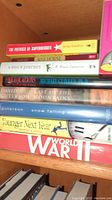 Books stacked on a wooden shelf including titles like The Physics of Superheroes, War Horse, A Dog's Journey, and others.