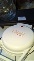 Closed view of Toastmaster Belgian waffle baker, white, with logo and indicator light visible