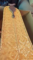 Close-up of woven rattan ceiling fan blade showing copper connector and housing