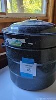 Side view of the assembled two tiered black enamel spattered canning pot with lid and label visible