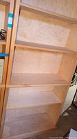 Front view of the light-finished wooden bookcase with five shelves visible