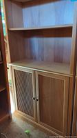 Front view showing double doors with vertical slats on lower cabinet and open shelves above.
