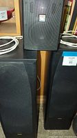Pair of JAMO 98 floor-standing speakers, front view with fabric grille covers on black speaker cabinets