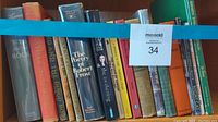 Shelf filled with vintage books, showing a variety of titles and colors on a wooden shelf.