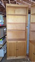 Front view of wooden bookshelf showing three adjustable shelves on top and double-door cabinet below.