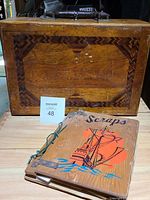 Front view of the wooden box with wood inlay and handle, showing inscription and the scrapbook placed in front.
