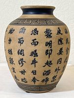Full front view of the vase showing the Chinese characters painted on the body and the geometric border pattern around the neck.