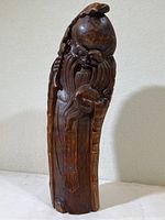 Full view of carved wooden figure showcasing the entire piece with visible bamboo-like grain and figure details.