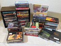 Large collection of DVDs stacked and arranged showing diverse titles and different case types, including box sets and individual DVDs.