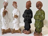Four ceramic figurines depicting traditional Chinese characters, showing variety in clothing and color schemes.
