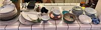 Wide view of the collection showing plates and bowls arranged on a counter, various sizes and patterns visible.
