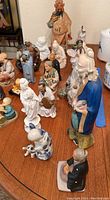 Overview photo showing around 20 porcelain figurines varying in size and character, arranged on a wooden table.