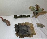 Overall collection of stone decorative pieces including carved fish, dish, and smaller carvings.