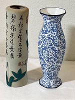 Pair of vases shown side by side on a white surface against a wall, highlighting their shapes, colors, and decorative patterns.