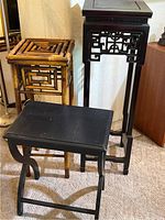Three Far East style display tables shown together; tallest black lacquered table with fretwork, medium height bamboo table, and lowest black lacquered table with curved legs.