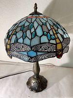 Front side view of Tiffany style stained glass lamp showing dragonfly design and metal base