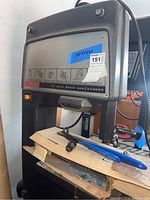 Front and side view of Craftsman band saw showing control panel with instructional stickers and power cord, work surface with some tools and guide attachment.