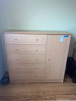 Front view of wooden dresser showing four drawers on the left and a cabinet door on the right.